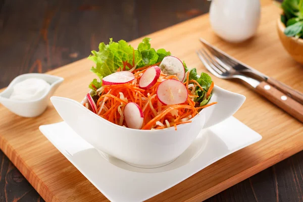 Ensalada de verduras en un plato blanco, tablero de madera y fondo . — Foto de Stock