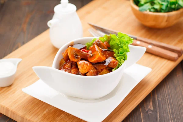 Жареные грибы в соусе на белой тарелке, деревянной доске и заднем плане . — стоковое фото