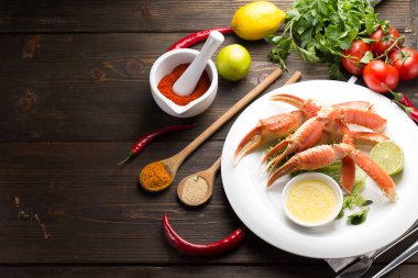 Haşlama yengeç pençeleri ile baharat ve sosu bir beyaz plaka ve ahşap arka plan