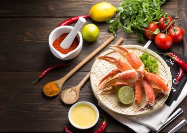 Haşlama yengeç pençeleri ile baharat ve sosu bir beyaz plaka ve ahşap arka plan