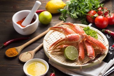 Haşlama yengeç pençeleri ile baharat ve sosu bir beyaz plaka ve ahşap arka plan