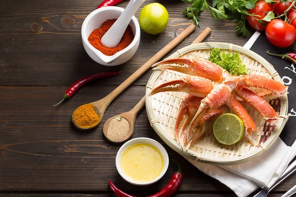 Garras de cangrejo hervidas con especias y salsa en un plato blanco y fondo de madera — Foto de Stock