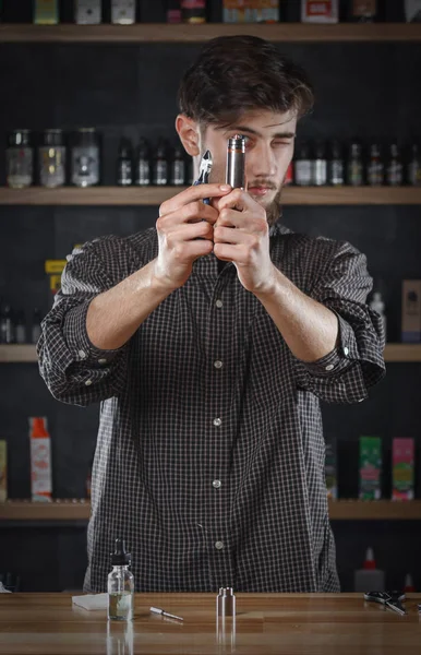 Seorang pria di toko vape mengisi cairan khusus dalam e-rokok . — Stok Foto