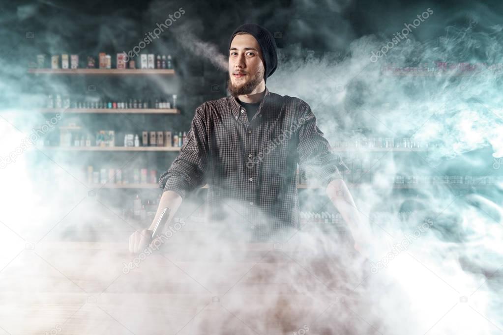 Vape shop. Man is smoking e-cigartte. Cloud of vapor.