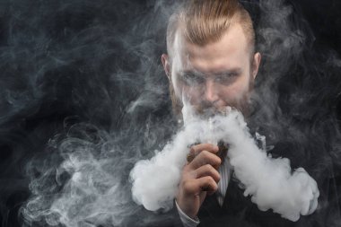 Bir mod tutarak Vaping adam. Buhar bulutu. Siyah arka plan. Stüdyo çekim.