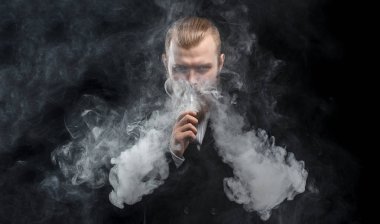 Bir mod tutarak Vaping adam. Buhar bulutu. Siyah arka plan. Stüdyo çekim.