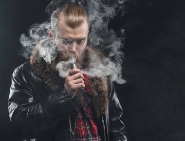 Bir mod tutarak Vaping adam. Buhar bulutu. Siyah arka plan. Stüdyo çekim.