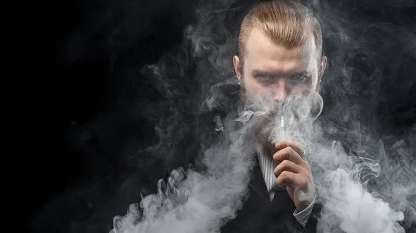 Vaping man innehar en mod. Ett moln av ånga. Svart bakgrund. Studio fotografering. — Stockfoto