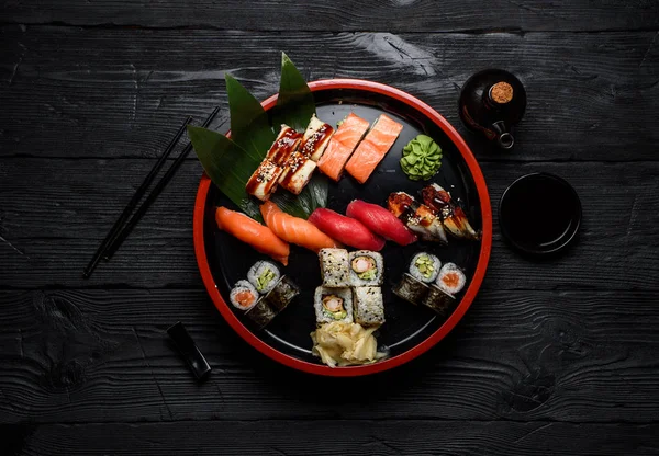 Японская кухня. Суши на круглой тарелке на темном деревянном фоне . — стоковое фото