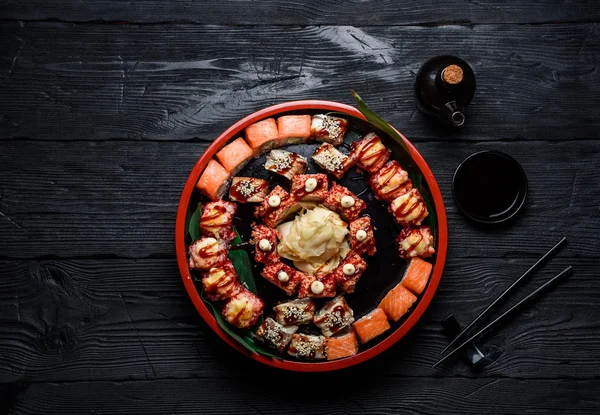 Japanische Küche. Sushi auf einem runden Teller vor dunklem Holzhintergrund. — Stockfoto