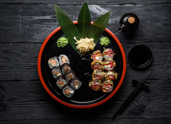 Japanska köket. Sushi som ligger på en rund platta över mörka trä bakgrund. — Stockfoto
