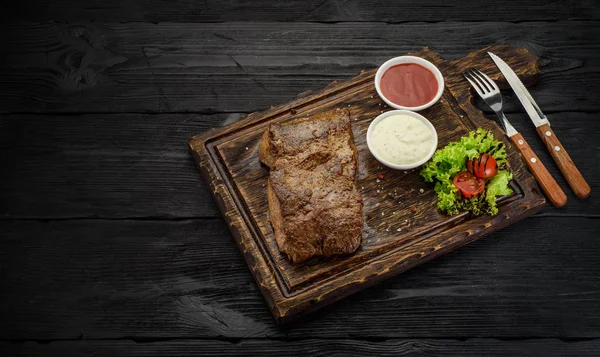 Grillezett marhahús steak szószok egy táblán. Sötét fából készült asztal. — Stock Fotó