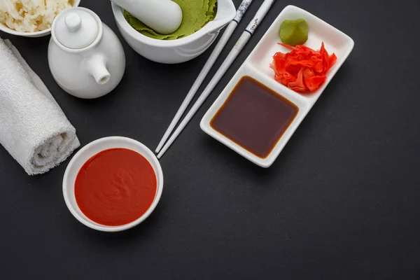 Instellen voor sushi. Sauzen, gember, wasabi, stokjes over donkere achtergrond. — Stockfoto