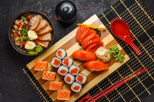 Japon mutfağı. Koyu arka plan üzerinde suşi kümesi ve ramen çorbası.