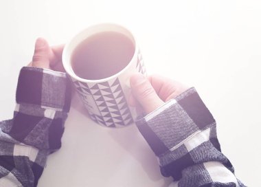 Erkeklerin elleri beyaz arka planda bir fincan sıcak çay tutuyor. Bir adam çay içiyor..