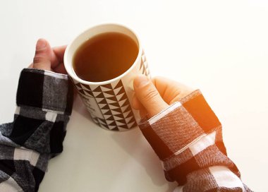 Erkeklerin elleri beyaz arka planda bir fincan sıcak çay tutuyor. Bir adam çay içiyor..