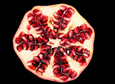 Pomegranate fruit cut in half on a black background