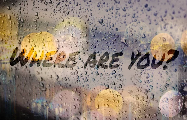 Question: Where are you? on fogged glass during rain. Words on glass in drops.