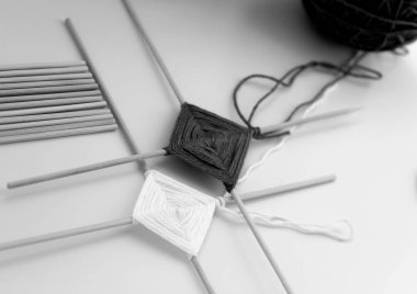 Ahşap çubuklarda renkli ipliklerden mandalalar örüyorlar..