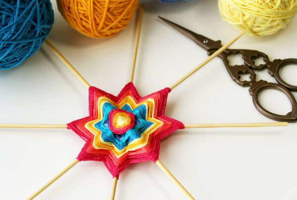 Wicker mandala made of blue yarn on wooden toothpicks. Flower  or star pattern.