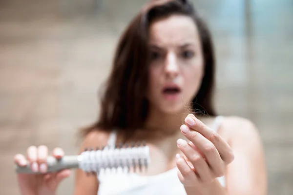 Morena mujer mirando asustado cuando ve un montón de pelo caído en el problema de pérdida de pelo cepillo —  Fotos de Stock