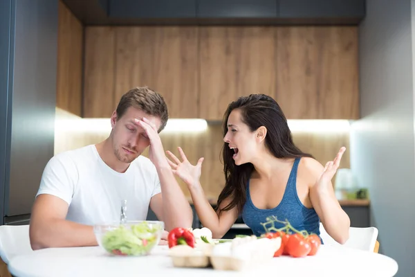 Unga par som bråkar medan matlagning frukost i köket fru ropar högt på sin man medan han ser irriterad familj gräl — Stockfoto