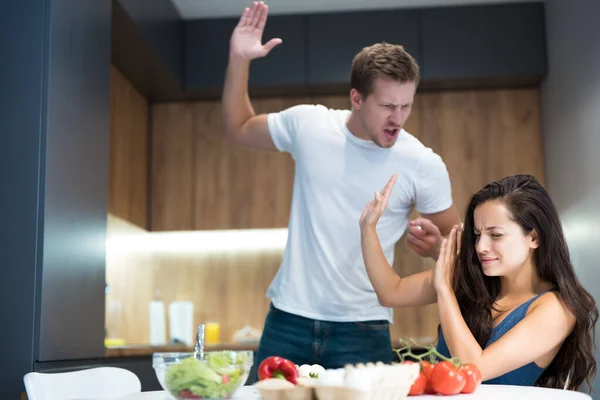 Giovane coppia avendo lotta durante la cottura della colazione in cucina marito alza il braccio contro la moglie mentre lei si allontana abusi domestici — Foto Stock