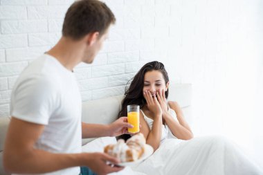 Genç adam lezzetli bir kahvaltı hazırladı - ay çöreği ve portakal suyu sevgili karısına mutlu bir sabah yemeği hazırladı.