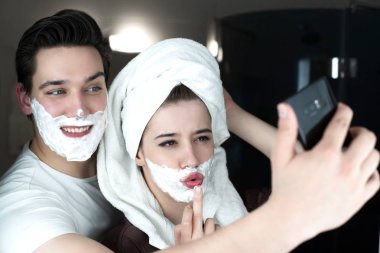Komik bir çift, yakışıklı bir adam ve güzel bir kadın selfie için poz veriyorlar. Komik görünüyorlar. Yüzlerinde tıraş köpüğü var.