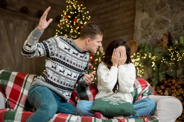 Jong paar met vechten man heffen zijn arm tegen zijn vrouw ruziën in kamer ingericht voor het vieren van het nieuwe jaar kerst familiedrama — Stockfoto