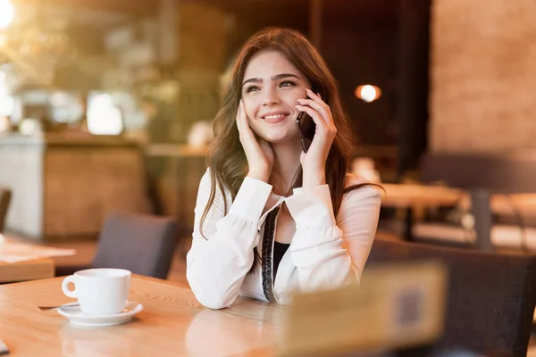 Joven sonriente mujer tener agradable charla telefónica trabajando fuera de la oficina durante la pausa para el almuerzo beber café caliente en la cafetería de moda buscando feliz mujer de negocios moderna — Foto de Stock
