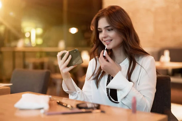 Νεαρή όμορφη γυναίκα βάζει κραγιόν της μετά την κατανάλωση ζεστό καφέ στο καφέ για μεσημεριανό γεύμα multitasking σύγχρονη επιχειρηματίας — Φωτογραφία Αρχείου