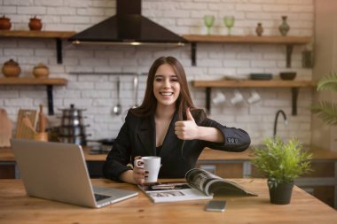 Gülümseyen güzel iş kadını. Günlük haberleri kontrol ediyor. Mutfakta dizüstü bilgisayar okuyor.