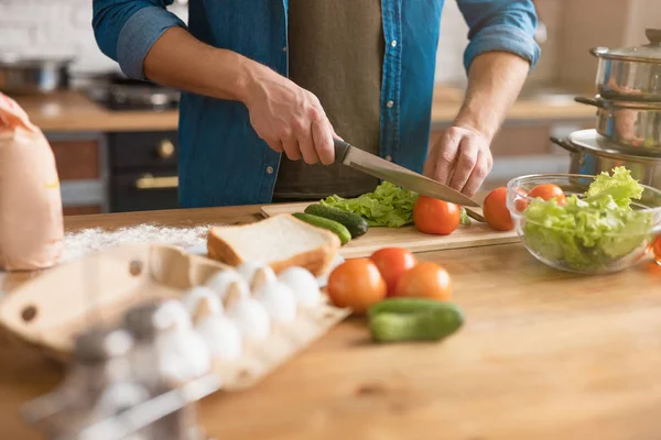 Bearbetning av hackning av grönsaker vid tillagning av sallad till lunch med kniv och träplatta — Stockfoto