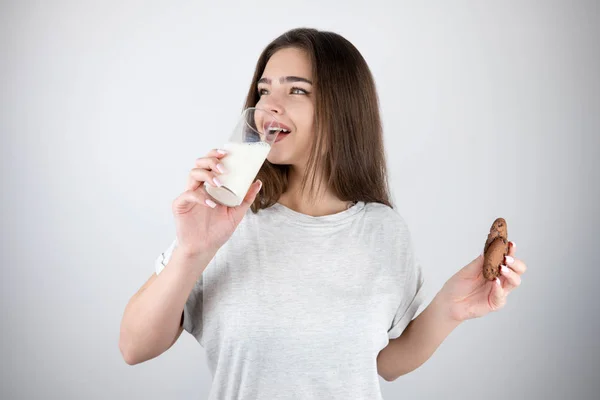 Jong mooi brunette vrouw drinken melk uit het glas holding chocolade cookie gezond levensstijl geïsoleerd wit achtergrond — Stockfoto
