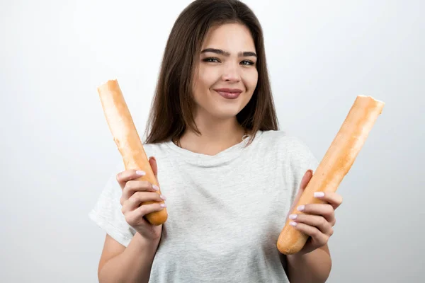 Jonge aantrekkelijke vrouw houden baguette verdeeld in twee delen in beide handen staan op geïsoleerde witte achtergrond dieet en voeding — Stockfoto