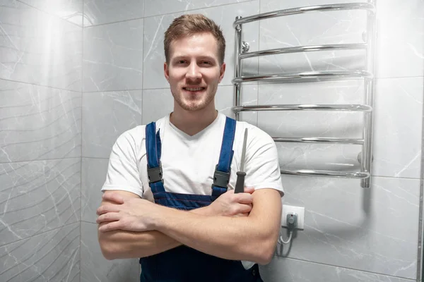 Sonriente hombre trabajador en uniforme con destornillador en la mano se ve feliz después de hacer el servicio de reparación profesional exitoso — Foto de Stock
