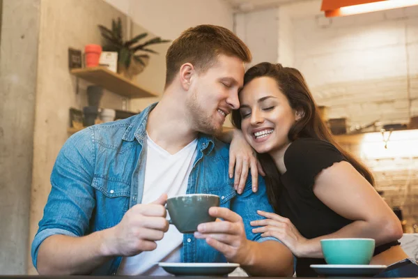 Hermosa pareja hermosa mujer y hombre guapo beber café caliente en la cafetería teniendo cita romántica inclinándose el uno al otro mirando feliz — Foto de Stock