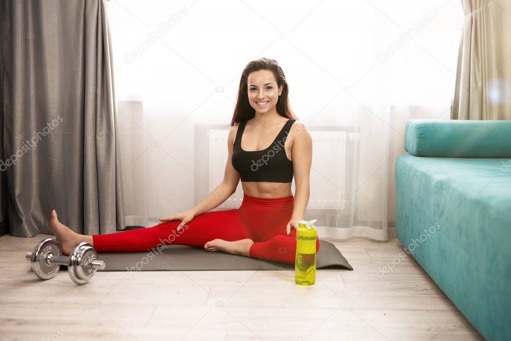 young fit brunette woman in sportwear stretching on the mat in living room after home workout, sportive lifestyle