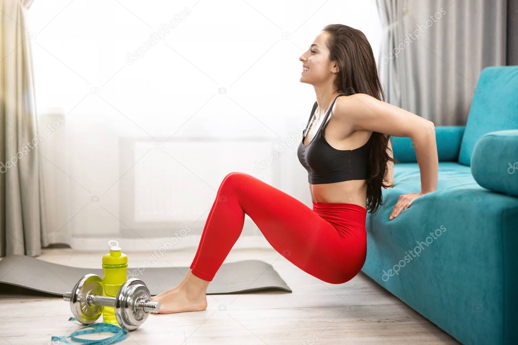 fit brunette woman in red leggings and black top doing everyday warm up home exercises on the floor, sportive lifestyle