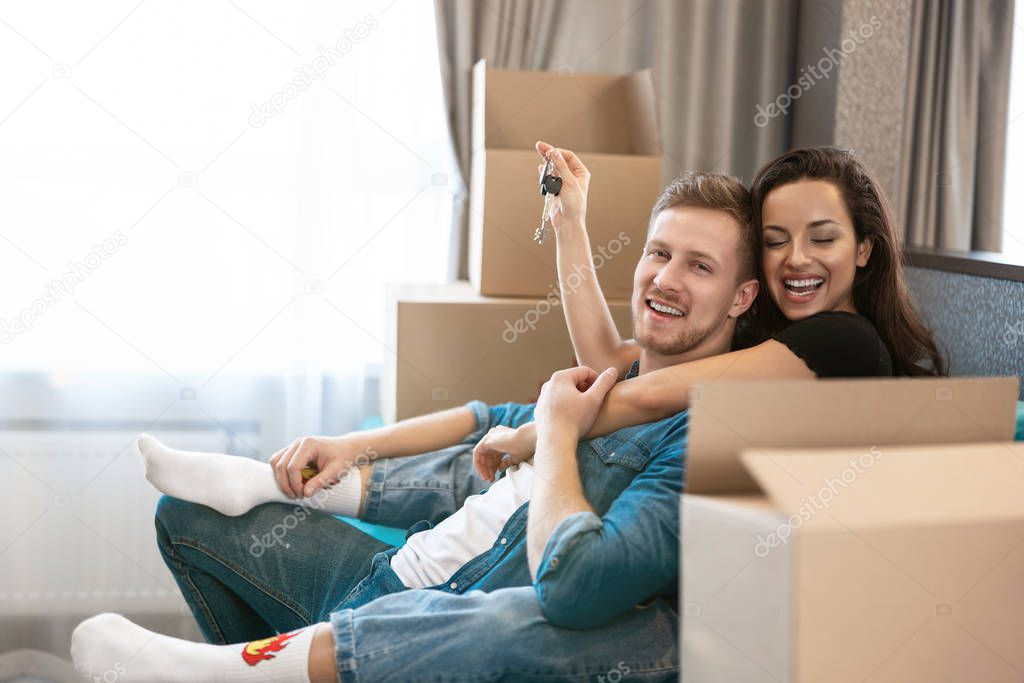 young couple man and woman looking happy having break on the sofa during moving to new appartment unpacking boxes, , moving process