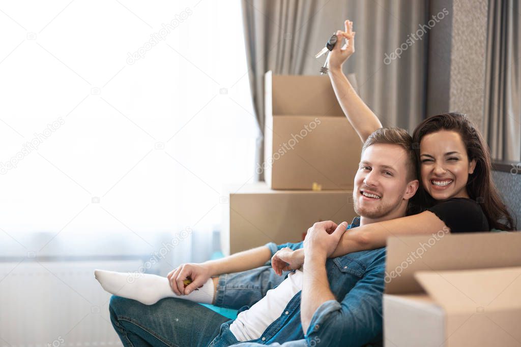 young couple man and woman looking excited having break on the sofa during moving to new appartment unpacking boxes, , moving process
