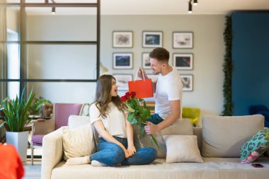 Sevgililer Günü 'nde çiçek ve hediyeyle sürpriz yapan genç adam, mutlu yıldönümleri.