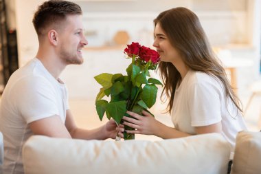 Genç yakışıklı adam sevgililer gününde güzel karısına güllerle sürpriz yapıyor. Romantik yıldönümleri kutlu olsun.