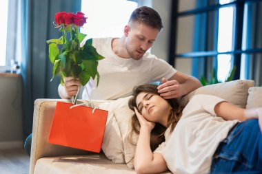 Genç ve yakışıklı bir adam, Aziz Sevgililer Günü 'nde güzel, uyuyan karısına güller ve hediyelerle sürpriz yapıyor. Mutlu romantik yıldönümleri.