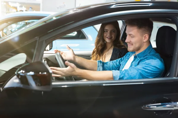 Gerente de mujer joven en traje de negocios consultando al cliente joven en el centro de concesionarios de automóviles eléctricos, cooperación profesional — Foto de Stock