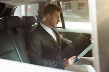 Genç işadamı, ortaklar ve çoklu görev kavramı ile buluşmadan önce arabasında sözleşme eğitimi alıyor.