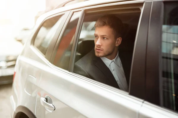stock image young businessman looking from the open car window, successful strategy concept
