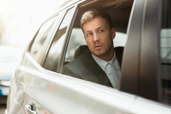 молодой бизнесмен смотрит из открытого окна автомобиля, успешная концепция бизнес-стратегии
