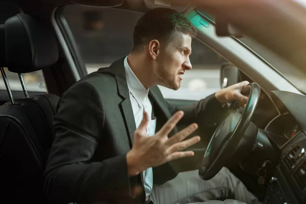 Młody zły biznesmen siedzi w samochodzie wygląda niespokojnie po ciężkim dniu w pracy, stresująca koncepcja warunków pracy — Zdjęcie stockowe